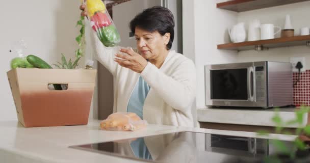 Oudere Biraciale Vrouw Die Alleen Keuken Groenten Uit Doos Pakt — Stockvideo