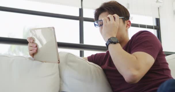Asian Male Teenager Wearing Glasses Using Tablet Living Room Spending — Vídeos de Stock