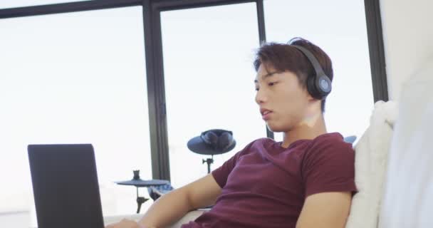 Щасливий Азіатський Підліток Носить Навушники Використовує Ноутбук Вітальні Проводити Час — стокове відео