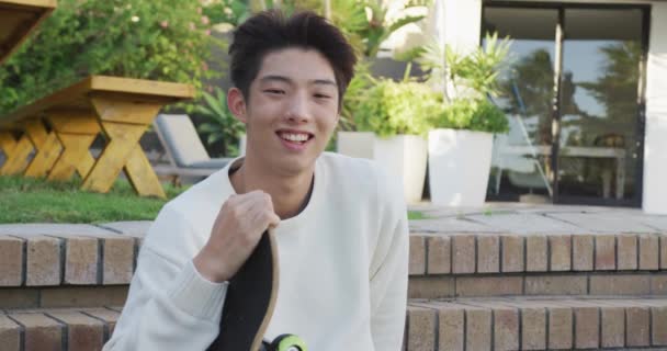 Portrait Happy Asian Male Teenager Sitting Skateboard Sunny Day Garden — Video