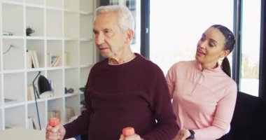 Kafkas kıdemli bir adamla egzersiz yapan mutlu kadın fizyoterapistin videosu. Yaşlılar sağlığı ve huzurevi konsepti dijital olarak oluşturulmuş video.