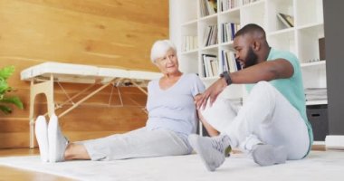 Afrika kökenli Amerikalı erkek fizyoterapistin beyaz yaşlı kadınla egzersiz yaptığı bir video. Yaşlılar sağlık ve huzurevi konsepti.