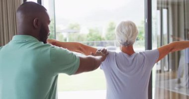 Afrika kökenli Amerikalı erkek fizyoterapistin beyaz yaşlı bir kadınla egzersiz yaptığını gösteren bir video. Yaşlılar sağlık ve huzurevi konsepti.