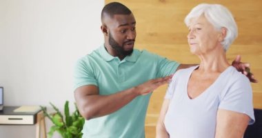 Afrika asıllı Amerikalı erkek fizyoterapistin beyaz yaşlı kadınla egzersiz yaptığı bir video. Yaşlılar sağlık ve huzurevi konsepti.