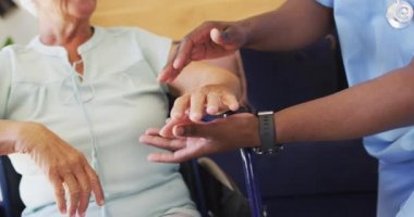 Kafkasyalı son sınıf kadınını destekleyen Afrikalı Amerikalı erkek doktorun videosu. Yaşlılar sağlık ve huzurevi konsepti.