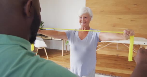 Video Happy Caucasian Senior Woman Exercising African American Male Physiotherapist — Wideo stockowe