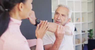 Kafkas kıdemli bir adamla egzersiz yapan mutlu kadın fizyoterapistin videosu. Yaşlılar sağlığı ve huzurevi konsepti dijital olarak oluşturulmuş video.