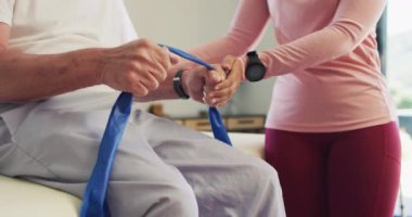 Kafkas kıdemli bir adamla egzersiz yapan mutlu kadın fizyoterapistin orta bölümünün videosu. Yaşlılar sağlığı ve huzurevi konsepti dijital olarak oluşturulmuş video.