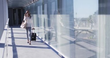 Bavullu ve akıllı telefon kullanan melez bir kadının videosu. İş adamları ve ofis kavramında çalışmak.