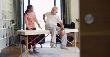 Kafkasyalı kıdemli adamı inceleyen melez kadın fizyoterapistin videosu. Yaşlılar sağlığı ve huzurevi konsepti dijital olarak oluşturulmuş video.