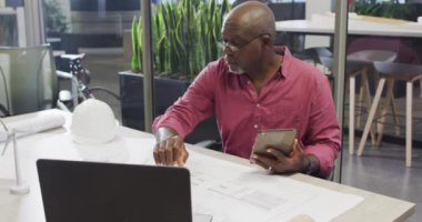 Projede tabletle çalışan odaklanmış Afro-Amerikan erkek tasarımcının videosu. İş adamları ve ofis kavramında çalışmak.