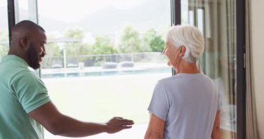 Afrika asıllı Amerikalı erkek fizyoterapistin beyaz yaşlı kadınla egzersiz yaptığı bir video. Yaşlılar sağlık ve huzurevi konsepti.