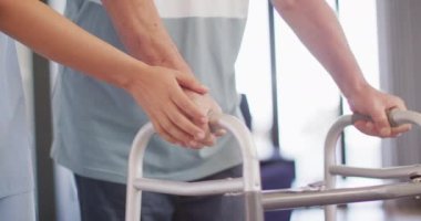 Animation of hands of biracial female doctor taking care of caucasian senior man. seniors health and nursing home lifestyle concept digitally generated video.