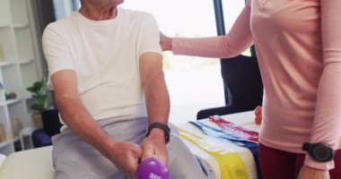 Kafkas kıdemli bir adamla egzersiz yapan mutlu kadın fizyoterapistin videosu. Yaşlılar sağlığı ve huzurevi konsepti dijital olarak oluşturulmuş video.