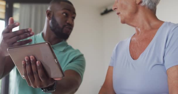 Video African American Male Physiotherapist Using Tablet Caucasian Senior Woman — Stock Video