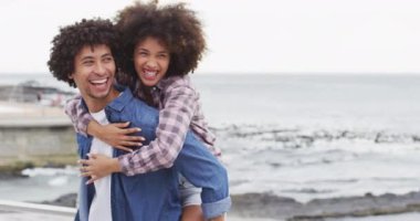 Afrikalı Amerikalı bir adam, sahil kenarındaki gezinti güvertesinde karısını sırtında taşıyor. Aşk ve ilişki kavramı