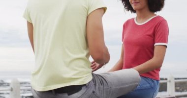 Afrika kökenli Amerikalı çift gezinti güvertesindeki bankta otururken birbirleriyle konuşurken gülümsüyor. Aşk ve ilişki kavramı