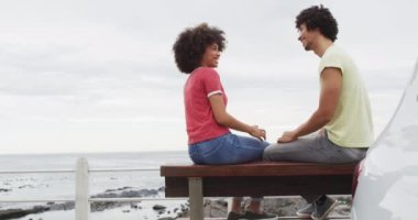 Afrika kökenli Amerikalı çift gezinti güvertesindeki bankta otururken birbirleriyle konuşurken gülümsüyor. Aşk ve ilişki kavramı