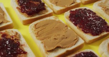 Close up of multiple peanut butter and jelly sandwiches on yellow surface. food and nutrition concept