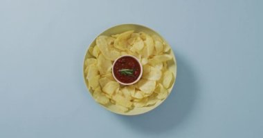 Mavi yüzeyinde sos olan bir kasede patates cipsi yakın. yiyecek ve atıştırmalık konsepti