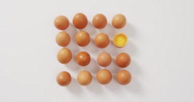 Close up of half broken egg with among other eggs on white surface. food and nutrition concept