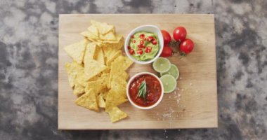 Close up of nachos and sauces on wooden tray on black surface. food and snack concept