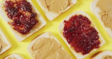 Close up of multiple peanut butter and jelly sandwiches on yellow surface. food and nutrition concept
