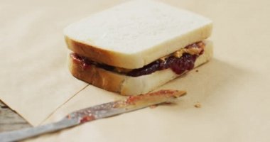 Close up of peanut butter and jelly sandwich and butter knife on wooden tray. food and nutrition concept