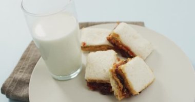 Close up of peanut butter and jelly sandwiches in a plate with milk on blue surface. food and nutrition concept