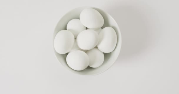 Sluiten Van Schaal Van Witte Eieren Met Kopieerruimte Wit Oppervlak — Stockvideo