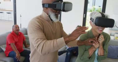 Happy senior diverse people using vr headsets at retirement home. healthy, active retirement and body inclusivity.