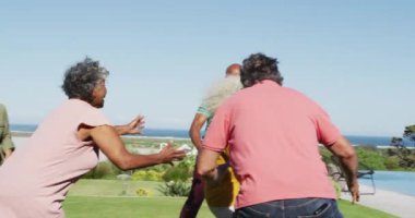 Happy senior diverse people playing rugby in garden at retirement home. healthy, active retirement and body inclusivity.