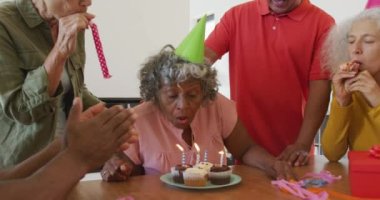 Happy senior diverse people at birthday party with cake at retirement home. healthy, active retirement and body inclusivity.