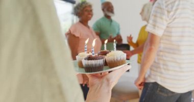 Happy senior diverse people at birthday party with cake at retirement home. healthy, active retirement and body inclusivity.