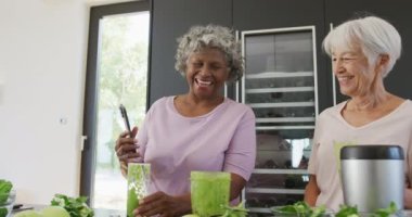 Huzur evinin mutfağında sağlıklı içecekler içen yaşlı ve çeşitli kadınlar. sağlıklı, aktif emeklilik ve bedensel bütünlük.