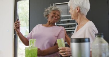 Huzur evinin mutfağında sağlıklı içecekler içen yaşlı ve çeşitli kadınlar. sağlıklı, aktif emeklilik ve bedensel bütünlük.
