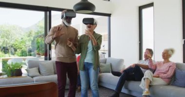 Happy senior diverse people using vr headsets at retirement home. healthy, active retirement and body inclusivity.