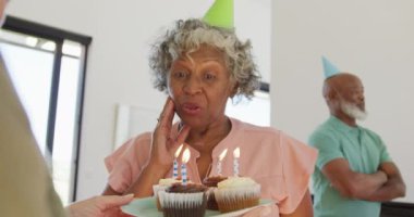 Happy senior diverse people at birthday party with cake at retirement home. healthy, active retirement and body inclusivity.