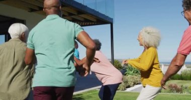 Happy senior diverse people playing rugby in garden at retirement home. healthy, active retirement and body inclusivity.