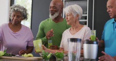 Happy senior diverse people making healthy drink in kitchen at retirement home. healthy, active retirement and body inclusivity.