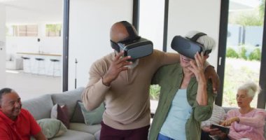 Happy senior diverse people using vr headsets at retirement home. healthy, active retirement and body inclusivity.