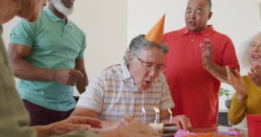 Happy senior diverse people at birthday party with cake at retirement home. healthy, active retirement and body inclusivity.