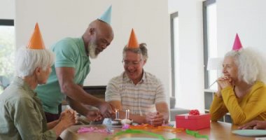 Happy senior diverse people at birthday party with cake at retirement home. healthy, active retirement and body inclusivity.