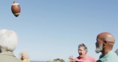 Happy senior diverse people playing rugby in garden at retirement home. healthy, active retirement and body inclusivity.