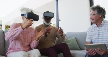 Happy senior diverse people using vr headsets at retirement home. healthy, active retirement and body inclusivity.