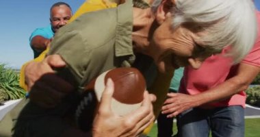 Happy senior diverse people playing rugby in garden at retirement home. healthy, active retirement and body inclusivity.