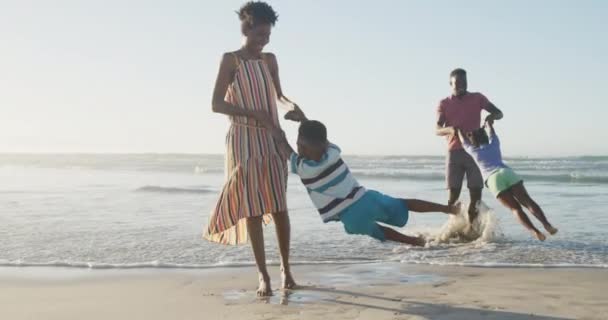 幸せなアフリカ系アメリカ人のカップルの娘と息子と日当たりの良いビーチで遊んでいる 健康的で活発な時間のビーチホリデー — ストック動画