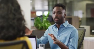 Odaklanmış Afro-Amerikan iş adamının bayan meslektaşıyla ofiste konuştuğu bir video. İş adamları ve ofis kavramında çalışmak.