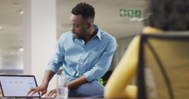 Odaklanmış Afro-Amerikan iş adamının bayan meslektaşıyla ofiste konuştuğu bir video. İş adamları ve ofis kavramında çalışmak.
