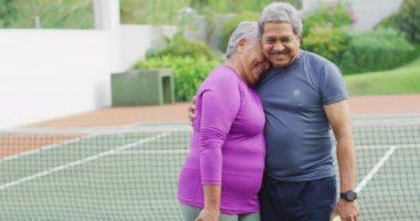 Tenis kortunda kucaklaşan mutlu son sınıf çifti videosu. aktif emeklilik yaşam tarzı, kıdemli ilişki ve tenis eğitim konsepti.